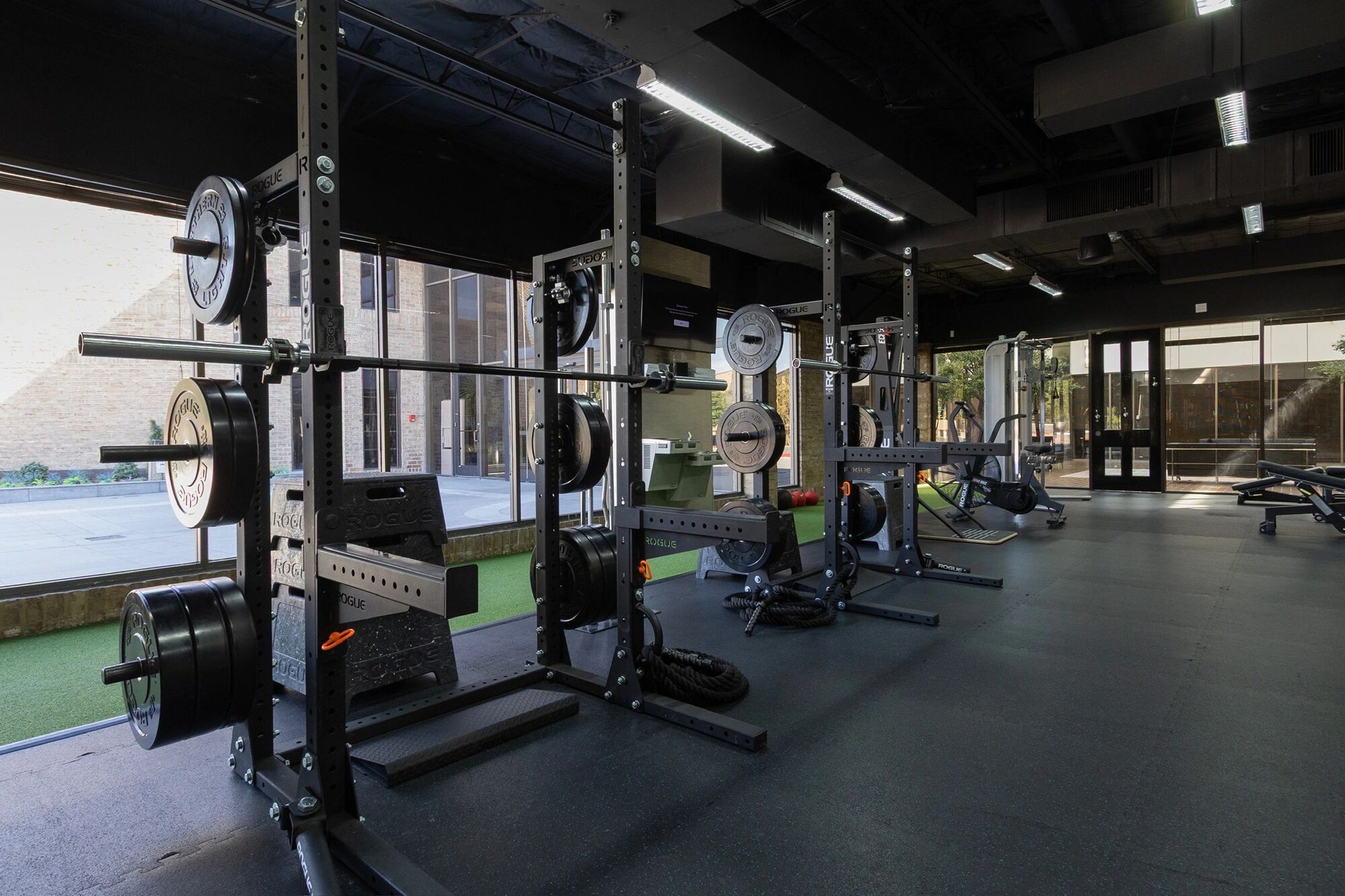 Squat racks and benches in the window light at The Athletic Club Houston